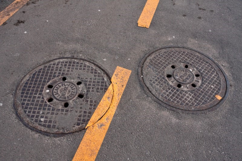 Two round manhole covers separated by dashed line